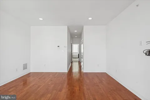 an empty room with wooden floor and bathroom