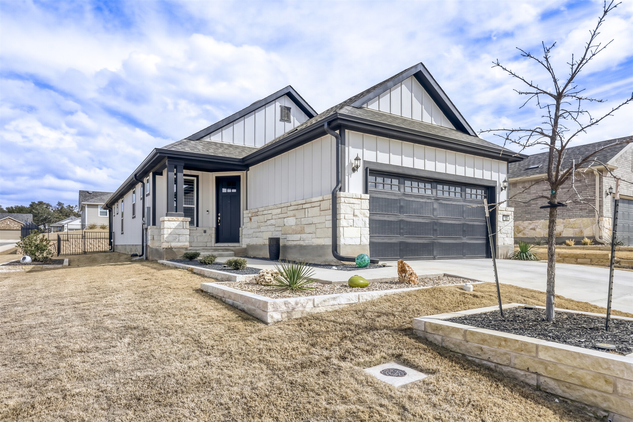 View of front of house with board and batten siding, stone siding, driveway, an attached garage, and roof with shingles