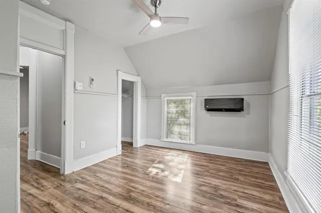 an empty room with wooden floor cabinet and windows