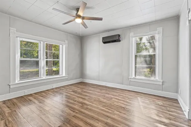 a view of an empty room with a window and wooden floor