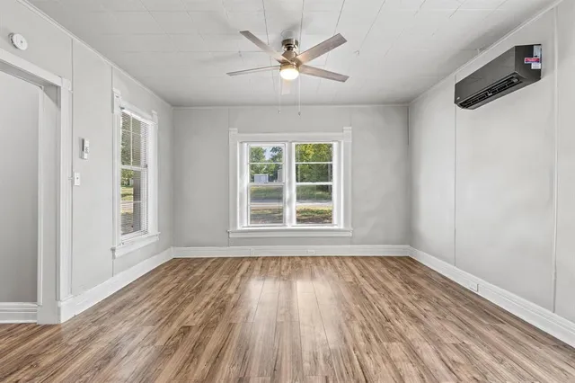 a view of an empty room with wooden floor and a window