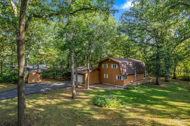 a view of a house with a yard deck and a small cabin