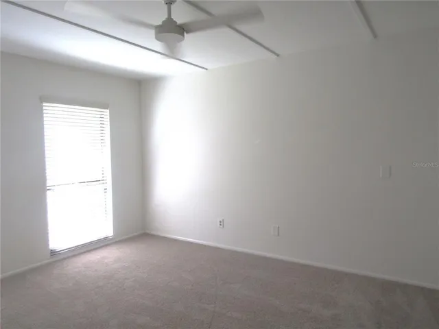an empty room with a window and a ceiling fan