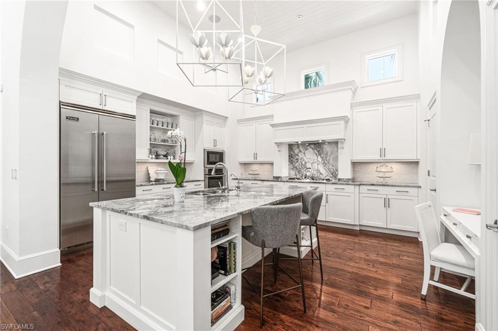 16755 Lucarno Way Naples, FL 34110 - Photo 8 of 50 a kitchen with stainless steel appliances granite countertop a table chairs and a refrigerator