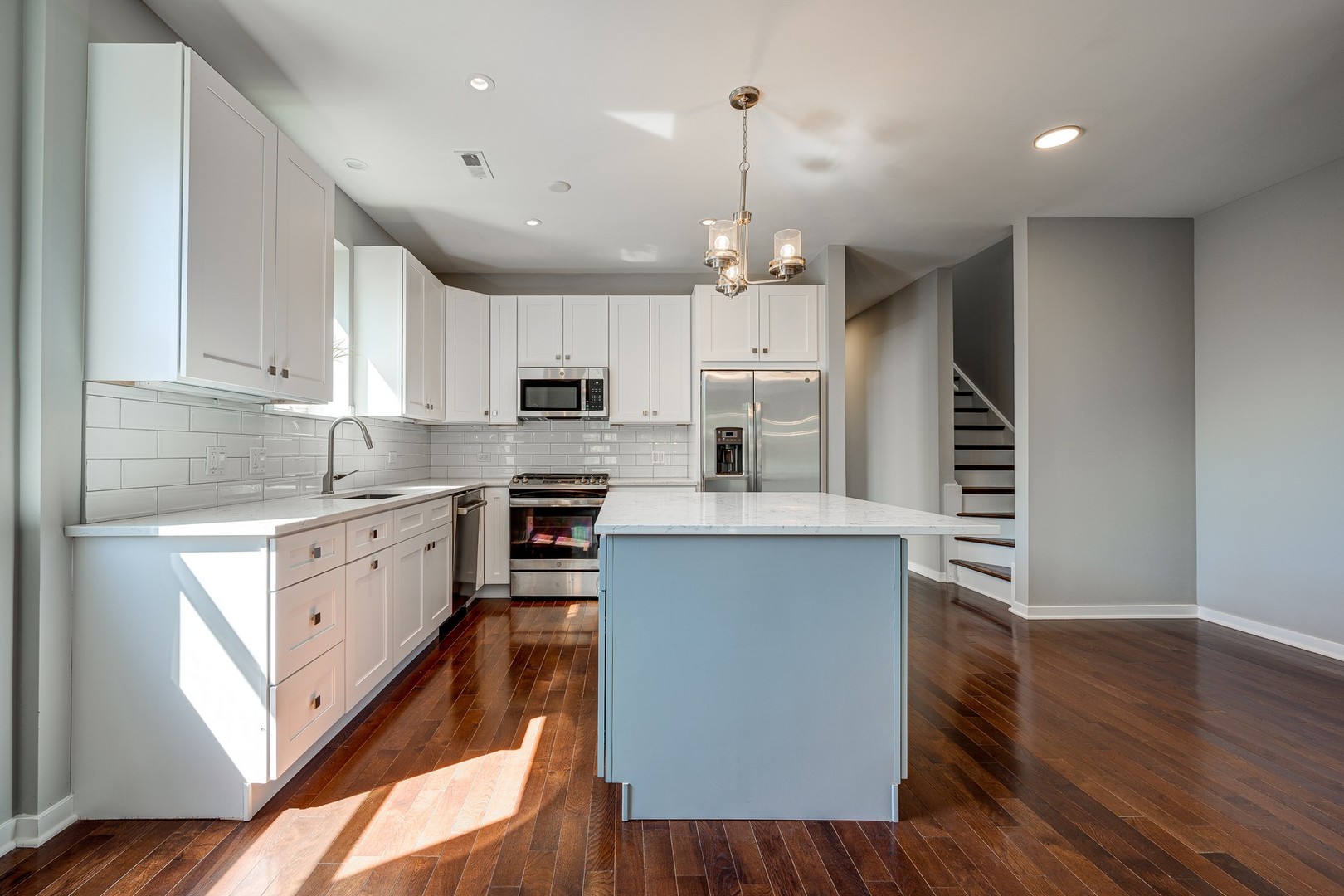 1038 South Racine Avenue, Unit 301 Chicago, IL 60607 - Photo 6 of 24 a kitchen with stainless steel appliances kitchen island granite countertop a stove a sink a refrigerator and white cabinets with wooden floor