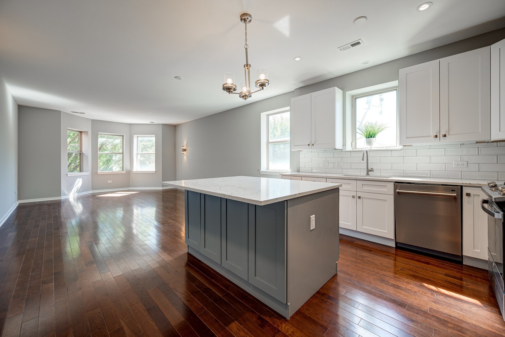 1038 South Racine Avenue, Unit 301 Chicago, IL 60607 - Photo 9 of 24 a kitchen with kitchen island granite countertop a stove a sink a center island and wooden floor