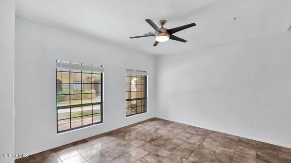 an empty room with windows and fan