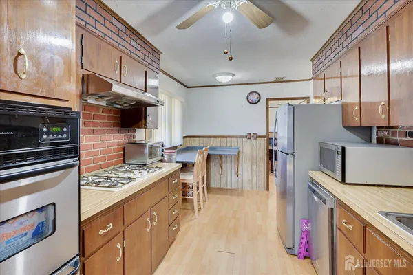 a kitchen with stainless steel appliances kitchen island granite countertop a refrigerator a stove and a wooden cabinets