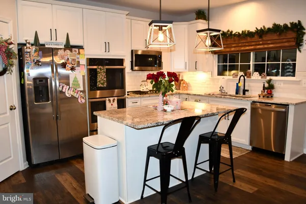 a kitchen with stainless steel appliances a dining table chairs stove refrigerator and cabinets