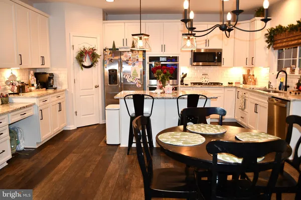 a kitchen with stainless steel appliances a dining table chairs and granite counter tops
