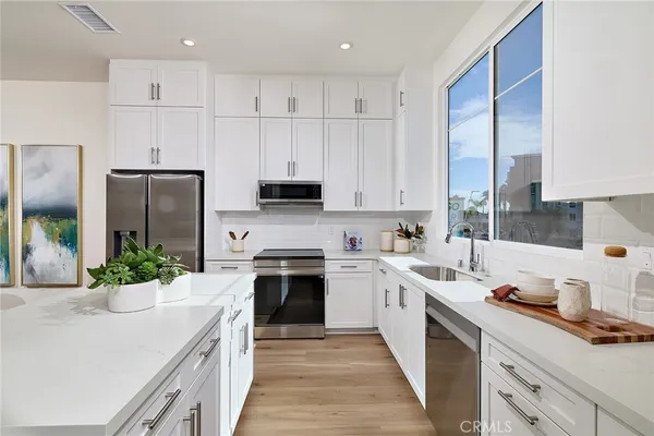 a kitchen with stainless steel appliances white cabinets a sink and a stove
