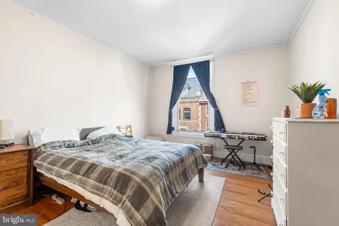 a bedroom with a bed and a potted plant on the dresser