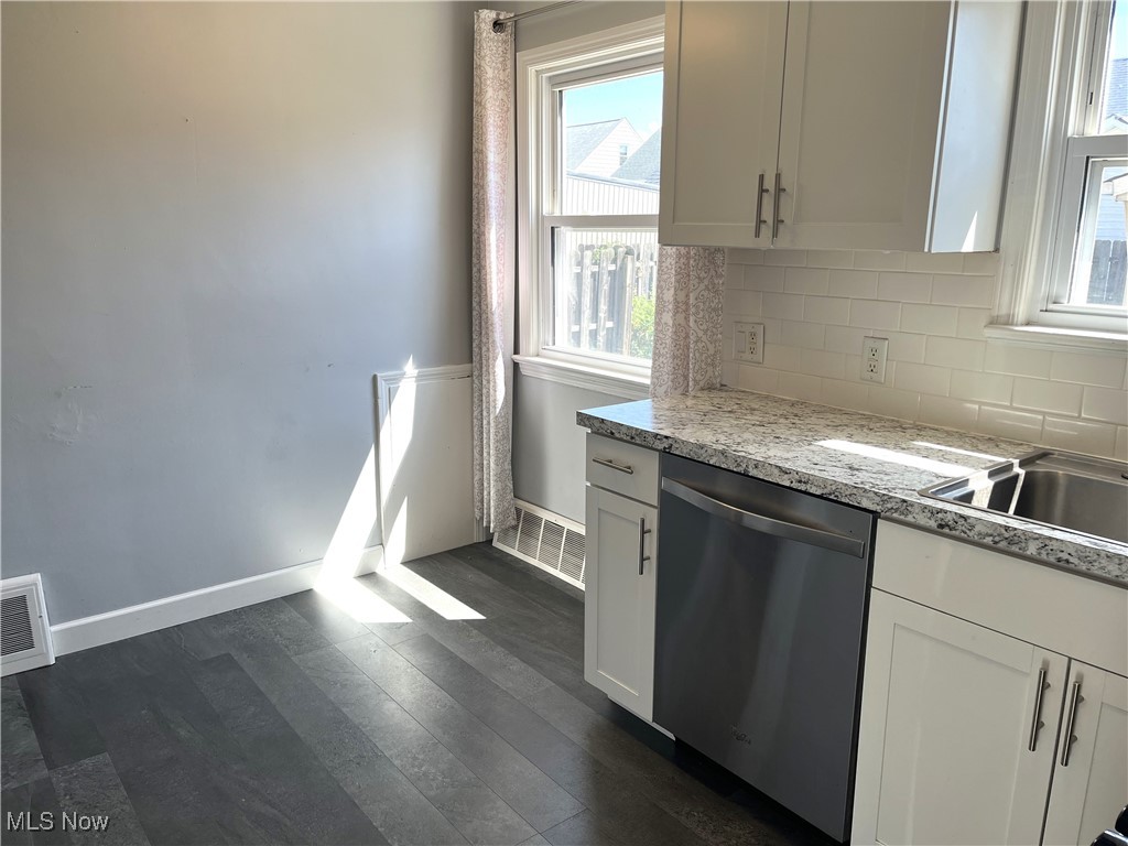 29946 Enid Road Wickliffe, OH 44092 - Photo 23 of 50 Kitchen featuring white cabinetry, stainless steel dishwasher, backsplash, and LTV flooring