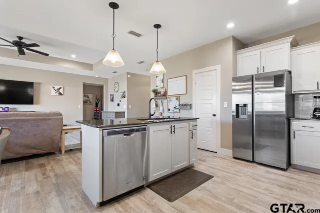 a kitchen with stainless steel appliances granite countertop a refrigerator a sink a stove and a wooden floors