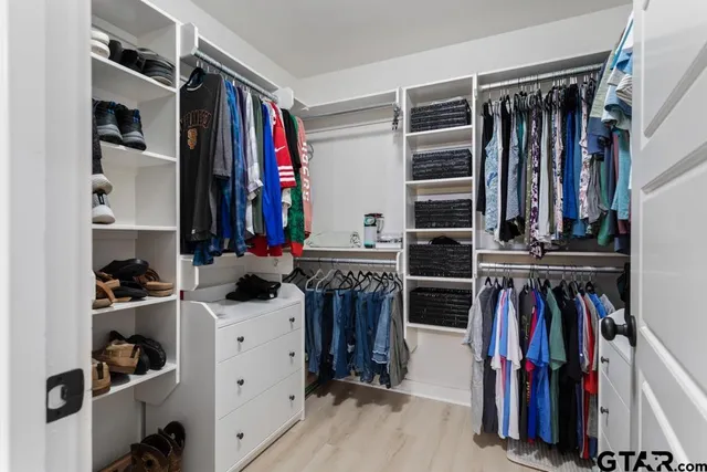 a view of walk in closet with clothes and shoes