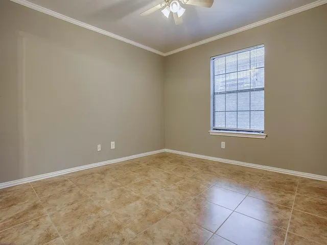 an empty room with windows and chandelier fan
