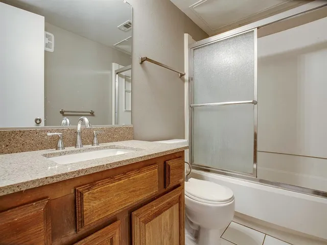 a bathroom with a granite countertop sink toilet mirror and a shower