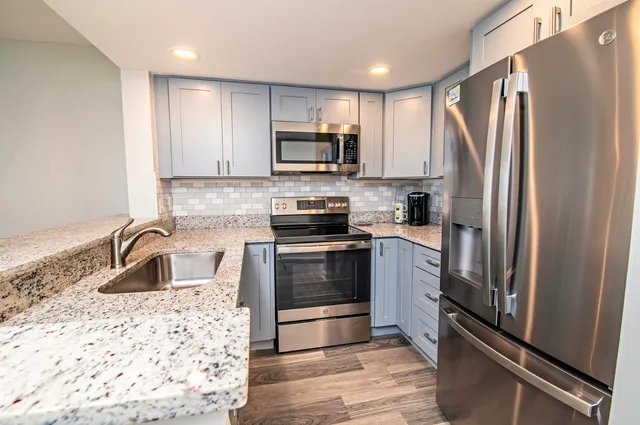 a kitchen with granite countertop a refrigerator stove and sink