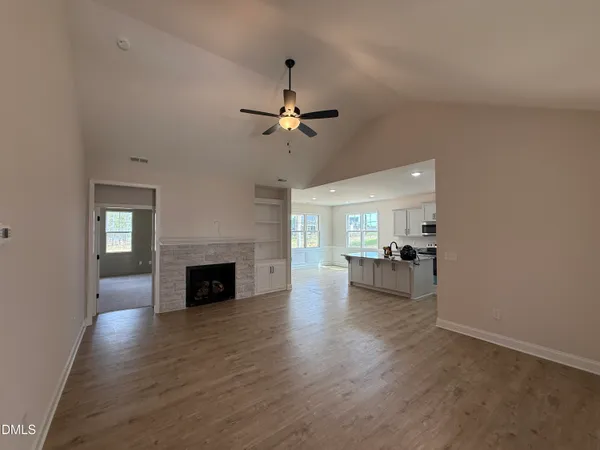 an empty room with fireplace chandelier fan and windows
