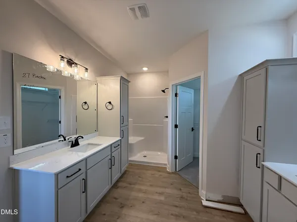 a spacious bathroom with a double vanity sink a large mirror and shower
