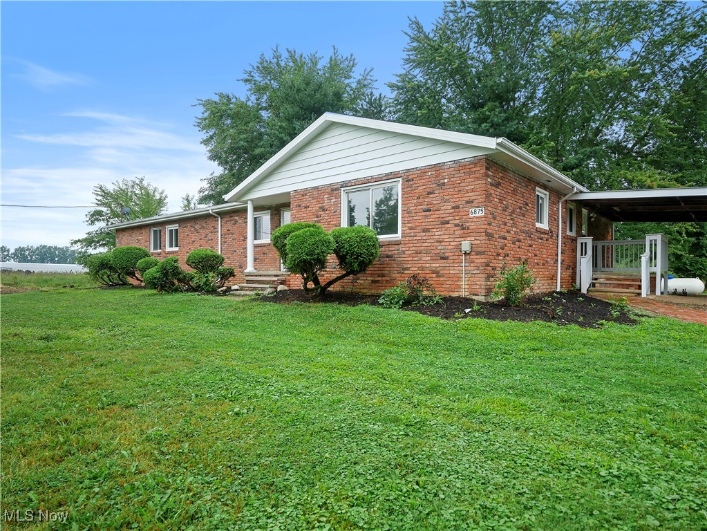 Ranch-style home with a carport, brick siding, and a front lawn