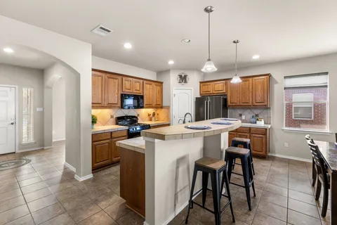 a dining room with furniture a chandelier and kitchen view