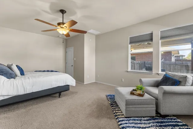a bedroom with a couch ceiling fan and a window