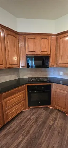 a kitchen with granite countertop wooden cabinets and a wooden floor