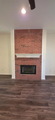 a view of an empty room with wooden floor and fireplace