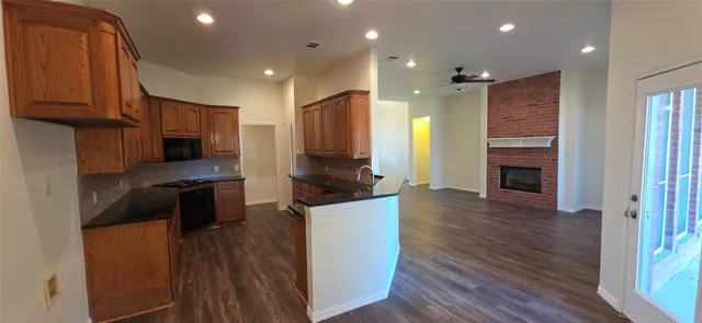 a large kitchen with stainless steel appliances granite countertop a stove a refrigerator a sink and a wooden floors