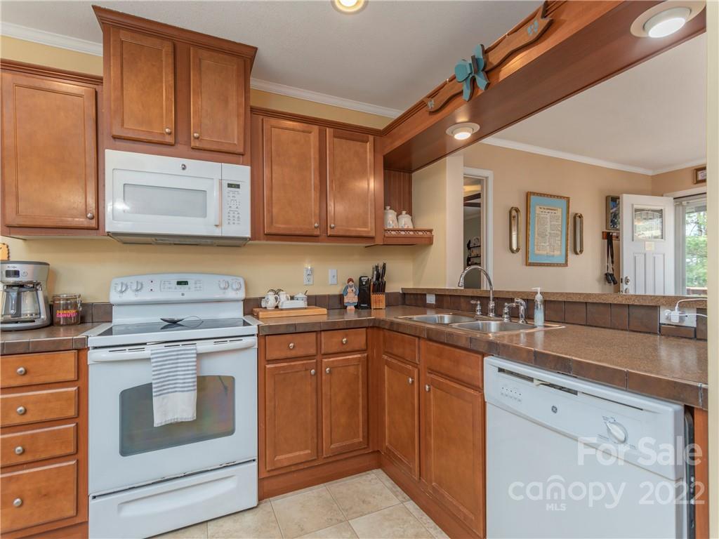6232 Panther Creek Road Clyde, NC 28721 - Photo 9 of 25 a kitchen with granite countertop a sink stainless steel appliances wooden cabinets and a counter top space
