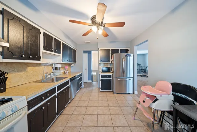 a kitchen with stainless steel appliances a sink a stove a refrigerator cabinets and dining table