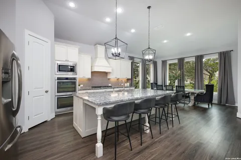 a kitchen with kitchen island granite countertop a sink a center island cabinets and stainless steel appliances