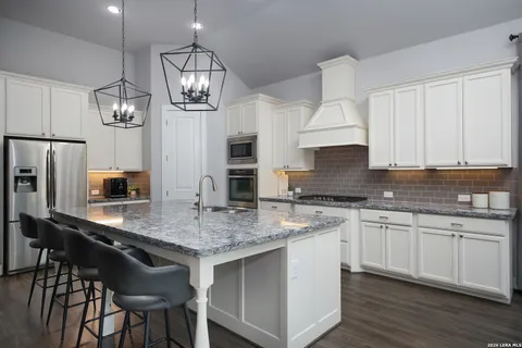 a large kitchen with granite countertop a sink stove and refrigerator