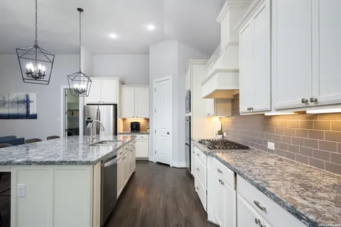 a kitchen with stainless steel appliances granite countertop a sink stove and cabinets