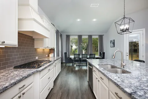 a kitchen with granite countertop stainless steel appliances a stove a sink and cabinets