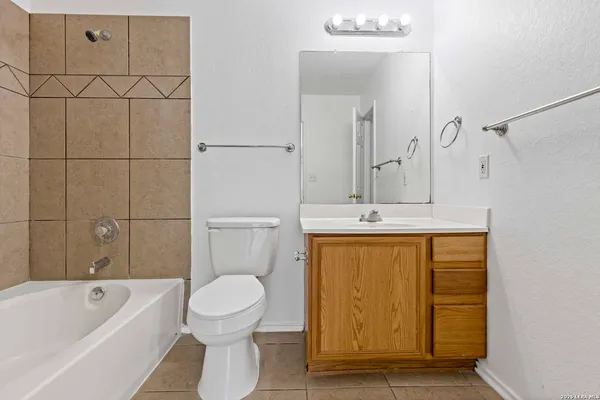 a bathroom with a granite countertop sink a toilet mirror and bathtub