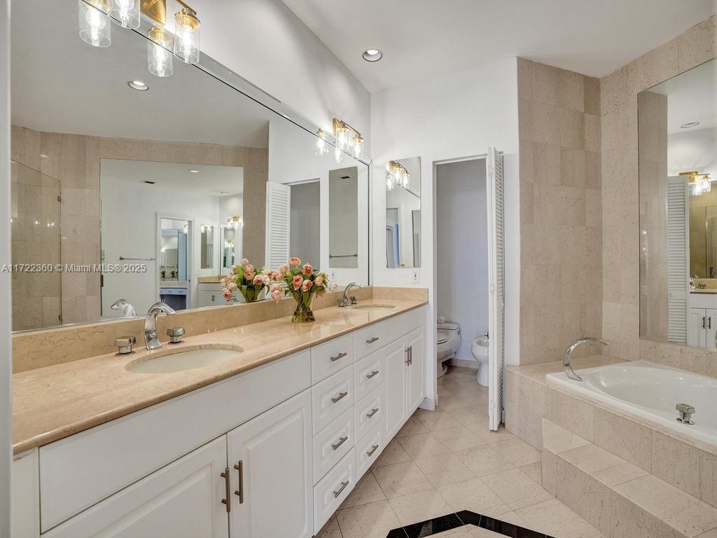 8850 Southwest 67th Court Pinecrest, FL 33156 - Photo 28 of 49 a bathroom with double vanity sinks a large mirror and a bathtub