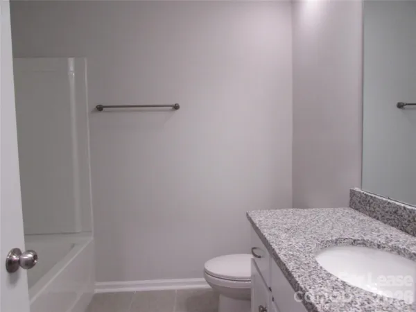 a bathroom with a granite countertop sink toilet and a mirror
