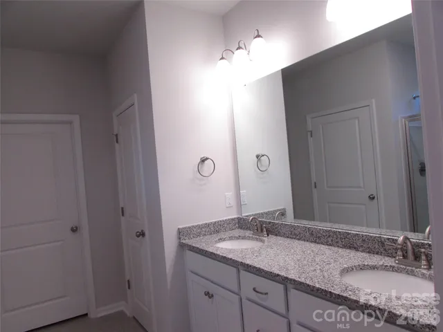 a bathroom with a granite countertop sink double and mirror