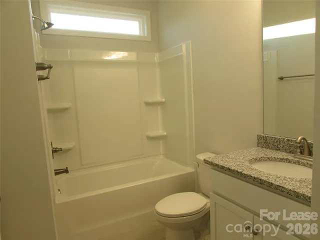 a bathroom with a granite countertop toilet a sink and shower