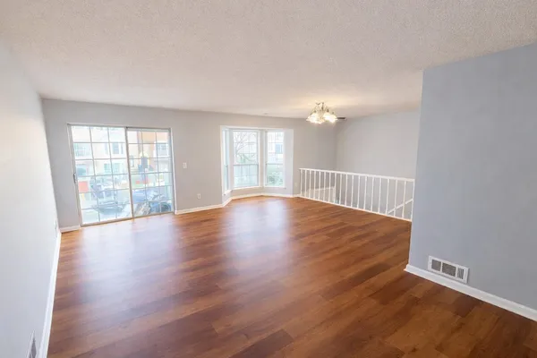 an empty room with wooden floor and windows