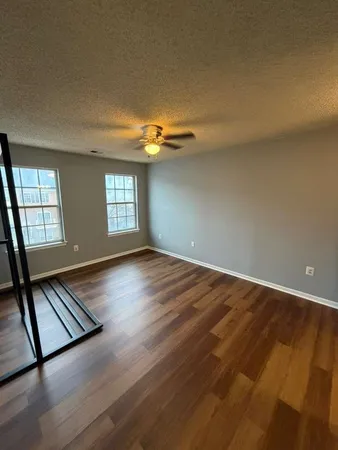 an empty room with wooden floor and windows