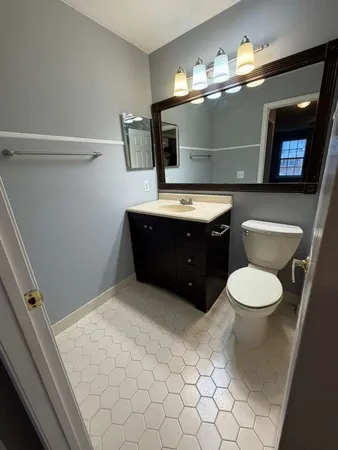 a bathroom with a toilet sink vanity granite and mirror