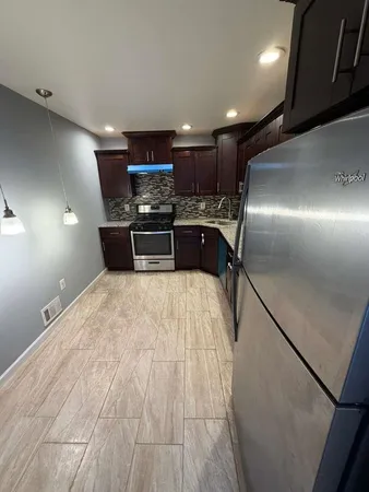 a kitchen with stainless steel appliances kitchen island granite countertop a refrigerator and a sink
