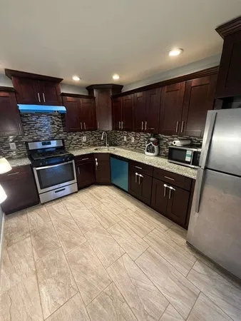 a large kitchen with stainless steel appliances granite countertop a stove a sink dishwasher and a refrigerator