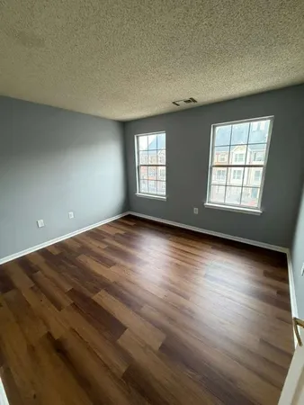 an empty room with wooden floor and windows