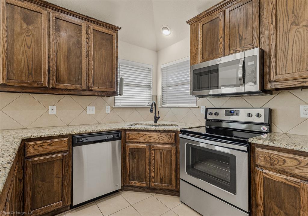 144 Birdsong Lane Terrell, TX 75160 - Photo 11 of 28 a kitchen with granite countertop cabinets stainless steel appliances and wooden cabinets