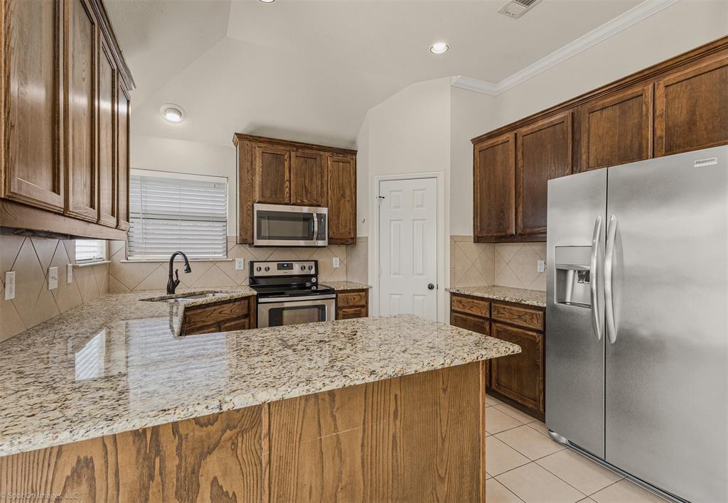 144 Birdsong Lane Terrell, TX 75160 - Photo 10 of 28 a kitchen with granite countertop a refrigerator and a sink