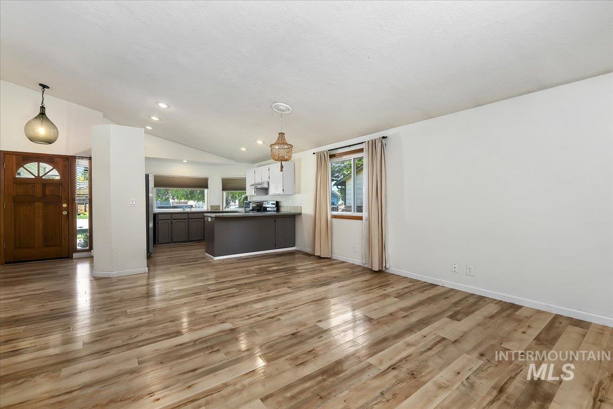 9215 West Preece Street Boise, ID 83704 - Photo 3 of 22 Expansive living area featuring wood-finish flooring and a vaulted ceiling
